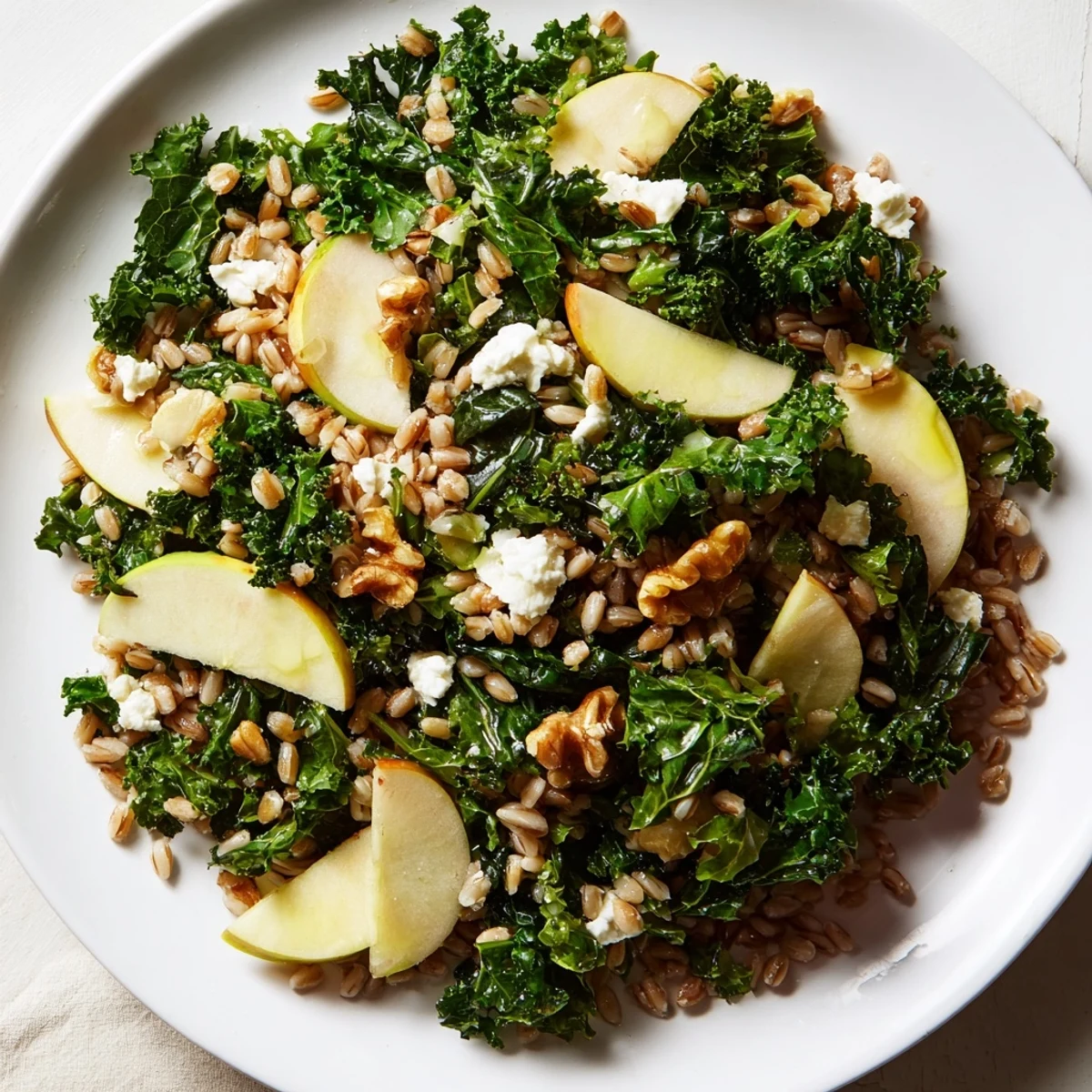 Savory Farro, Apple, and Warm Kale Salad, tossed in zesty dressing, perfect for a cozy, healthy meal.