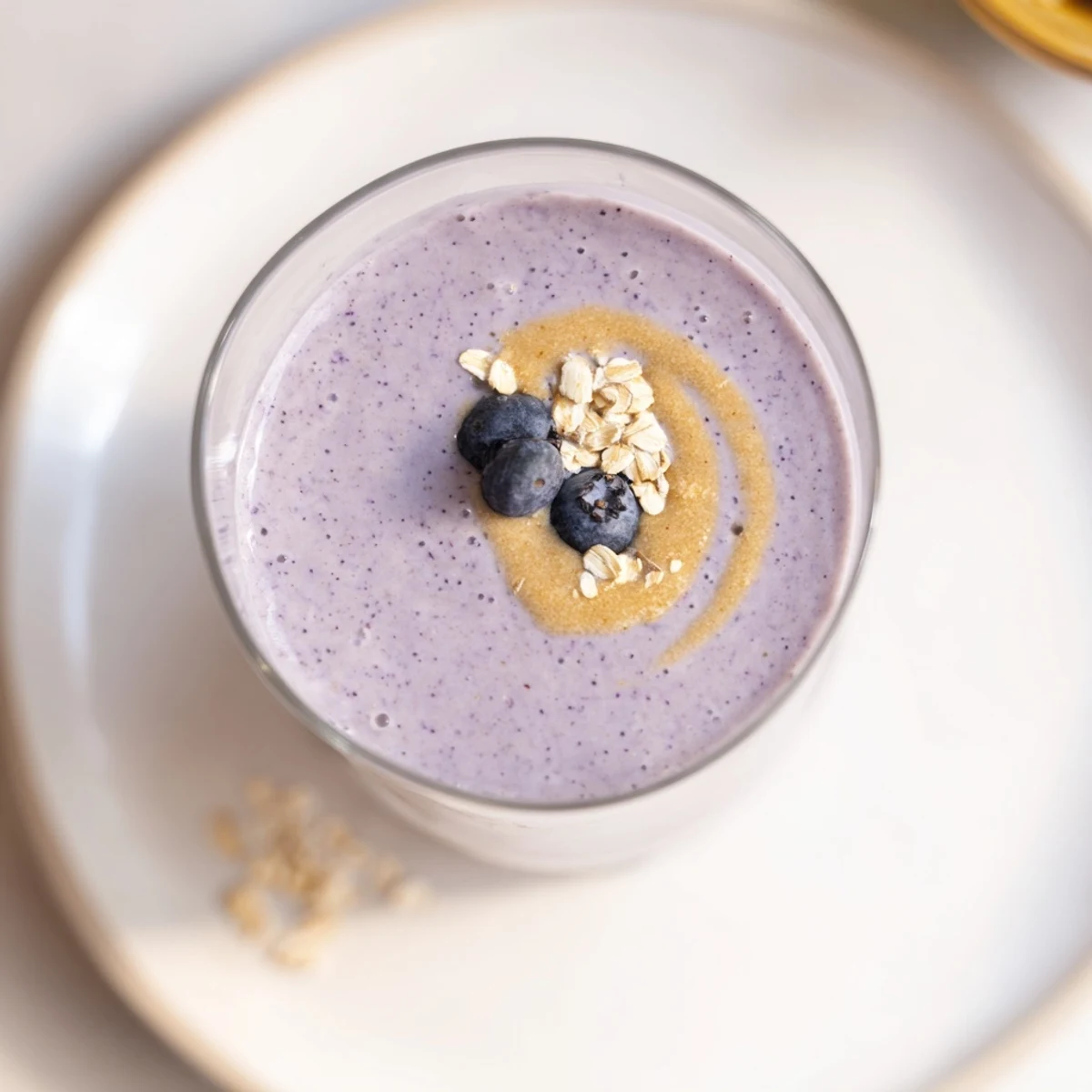 Bright photo of a blended Blueberry Brown Butter Oat Smoothie, with swirled textures from oats and blueberries.
