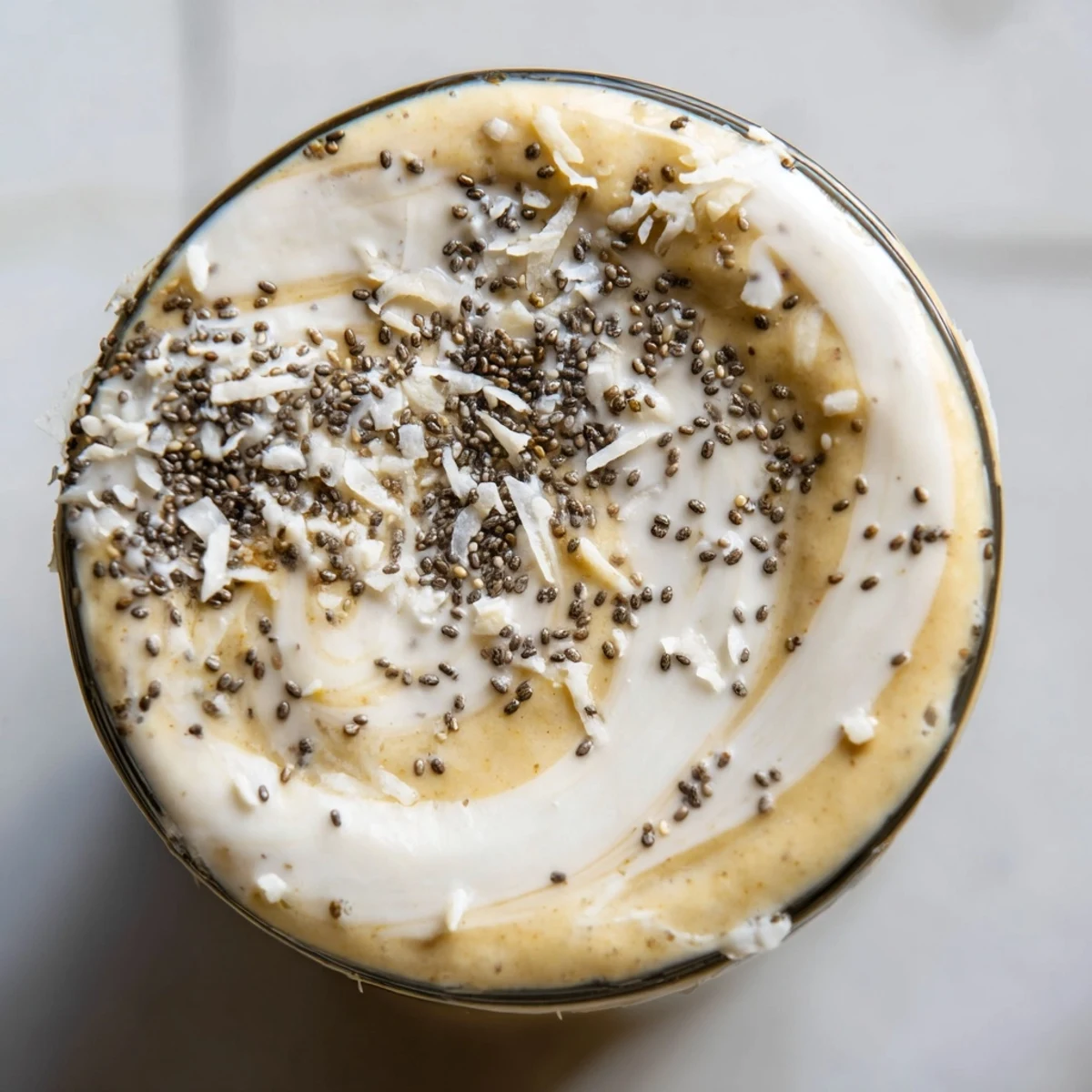 Creamy Coconut Collagen-Free Smoothie with Miso Glaze layered in a glass with shredded coconut garnish.