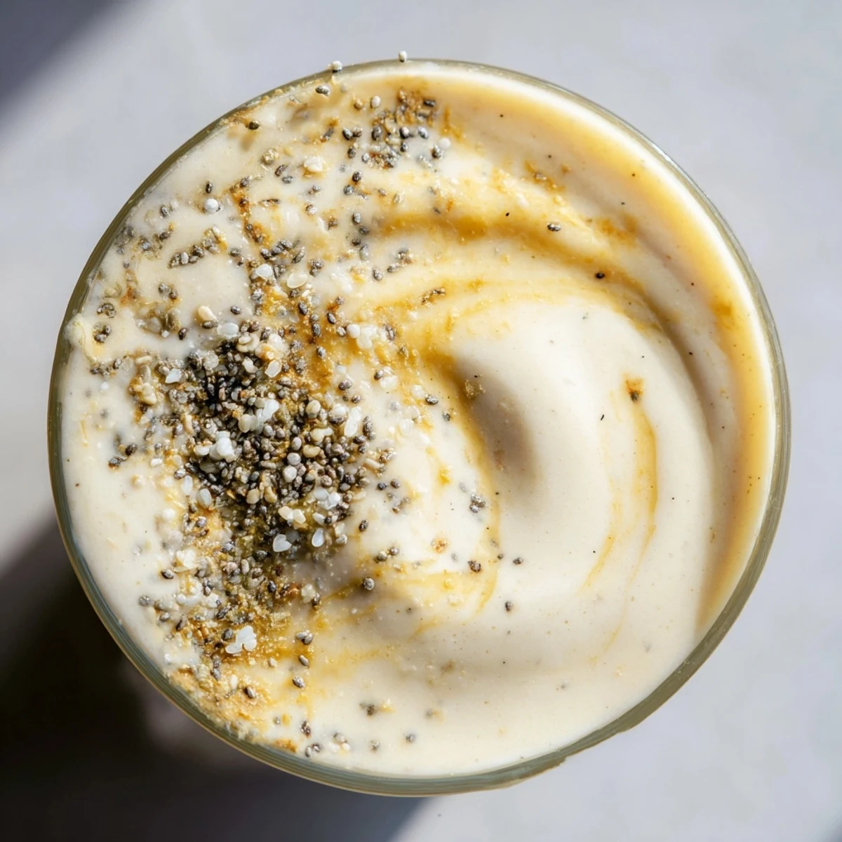Overhead view of a blender-ready Coconut Collagen-Free Smoothie with Miso Glaze beside tropical fruit ingredients.