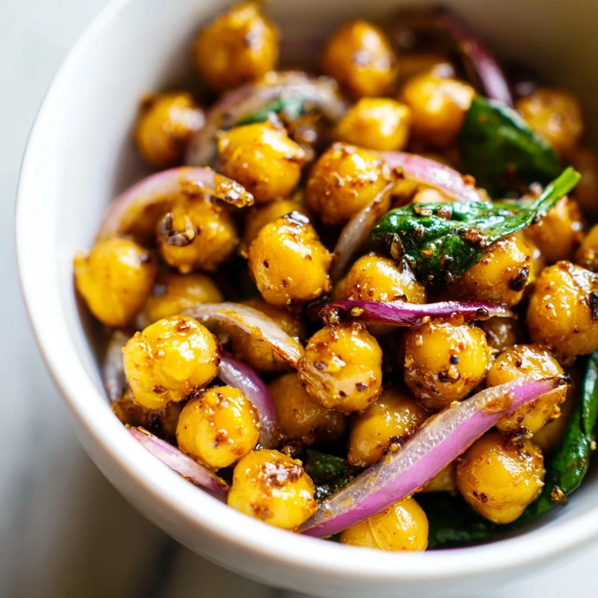 Glossy honey-glazed chickpeas and vibrant vegetables sizzling in a skillet with turmeric and spices.