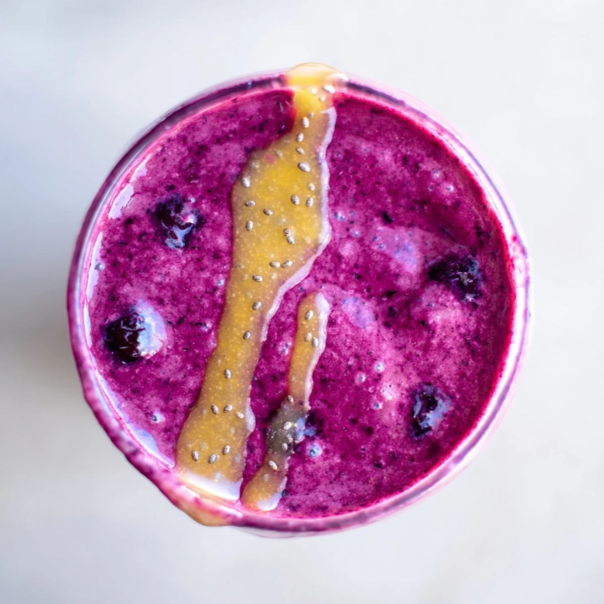 Thick and creamy Honey Glazed Winter Berry Smoothie in a tall glass, topped with a sweet honey drizzle.