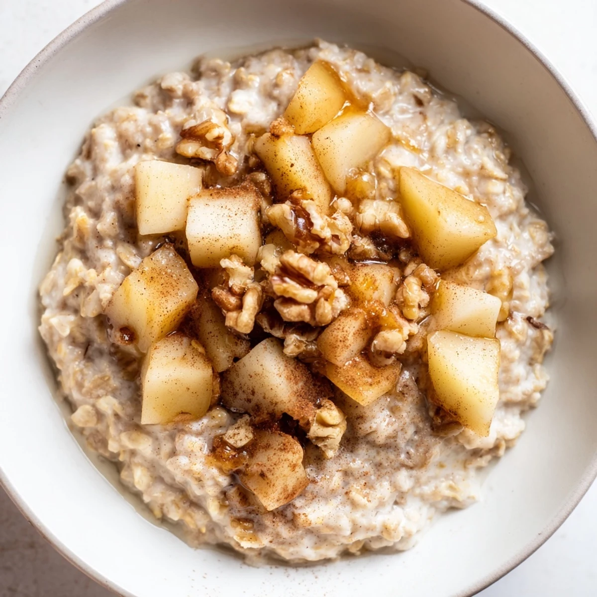 A warm bowl of Spiced Vanilla Scented Porridge topped with diced pears and a drizzle of maple syrup for a cozy morning breakfast.