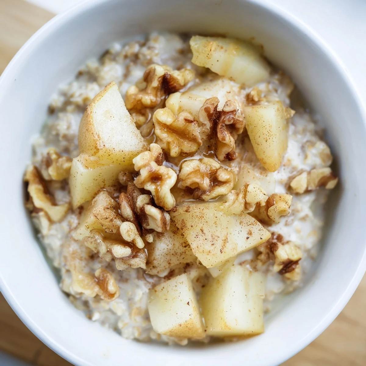 Creamy Spiced Vanilla Scented Porridge simmering in a pot with cinnamon sticks and fresh pear slices, ready to be served.