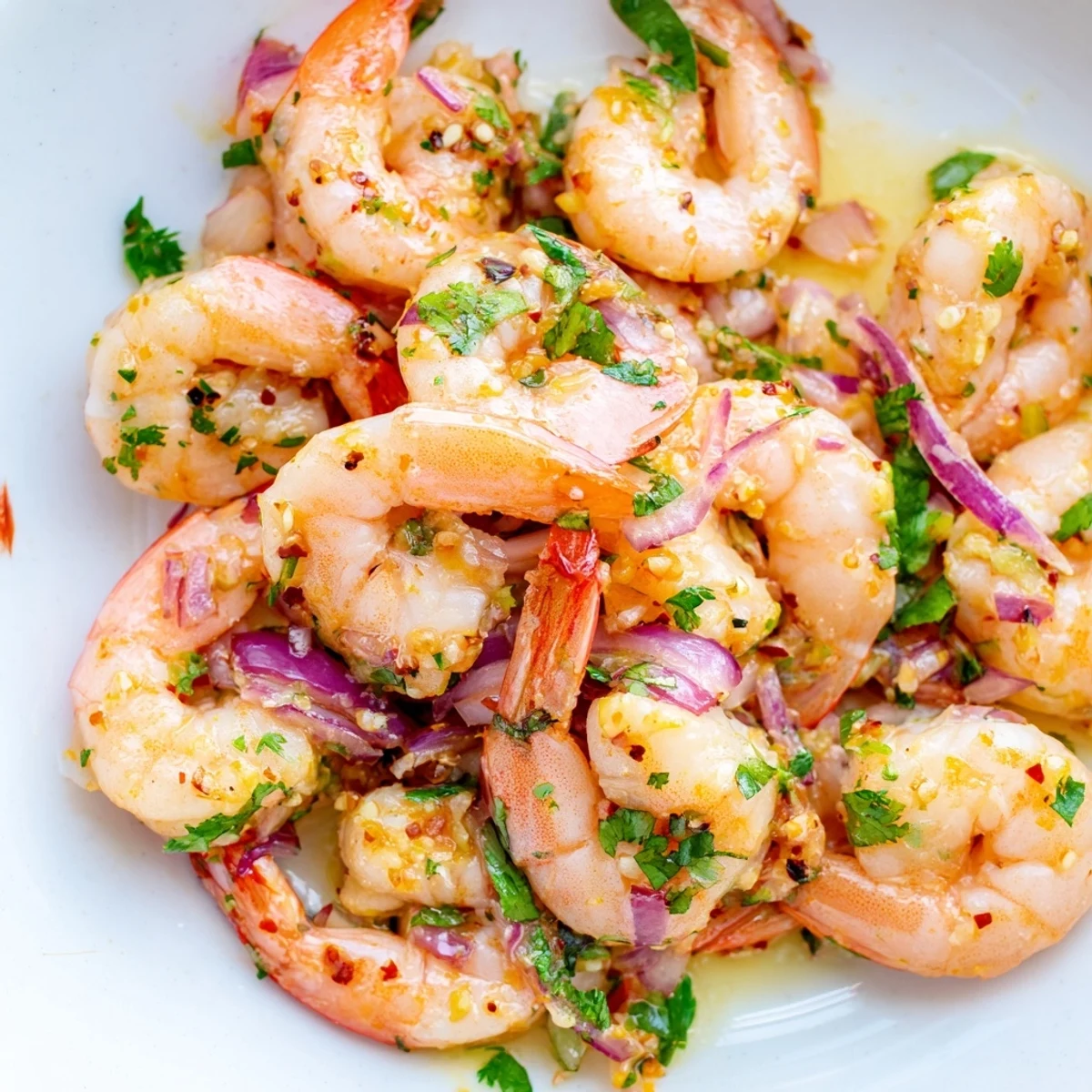 Colorful Cilantro Lime Shrimp tossed with thin red onion and sweet orange segments on a rustic white serving platter.