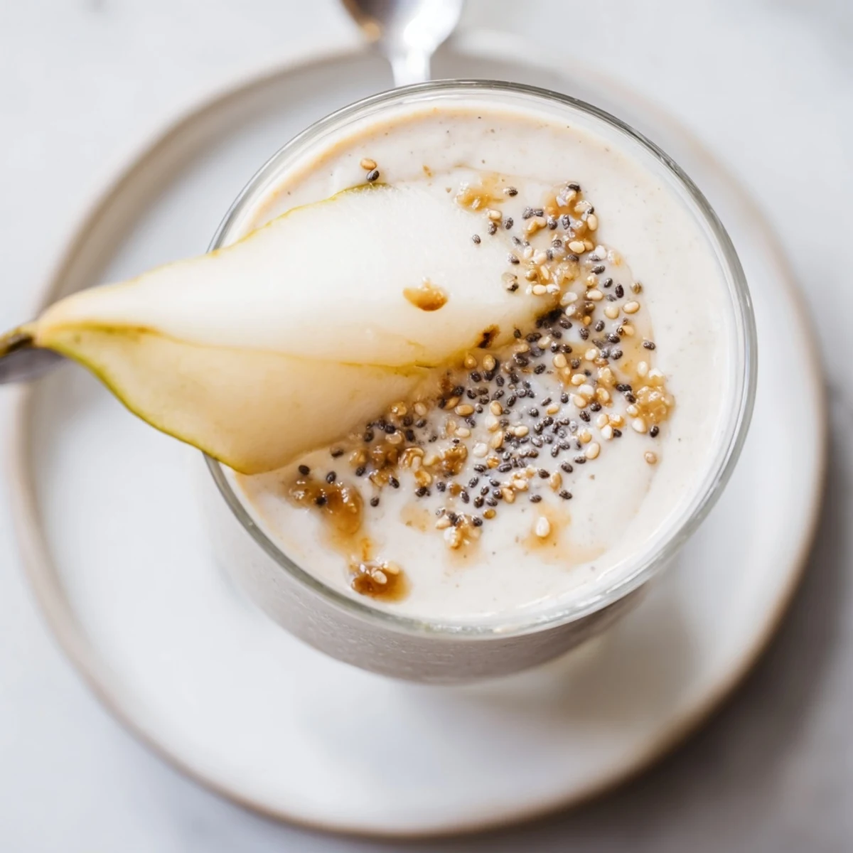 Creamy Miso Glazed Pear Ginger Smoothie in a glass topped with fresh pear slices and a drizzle glaze.