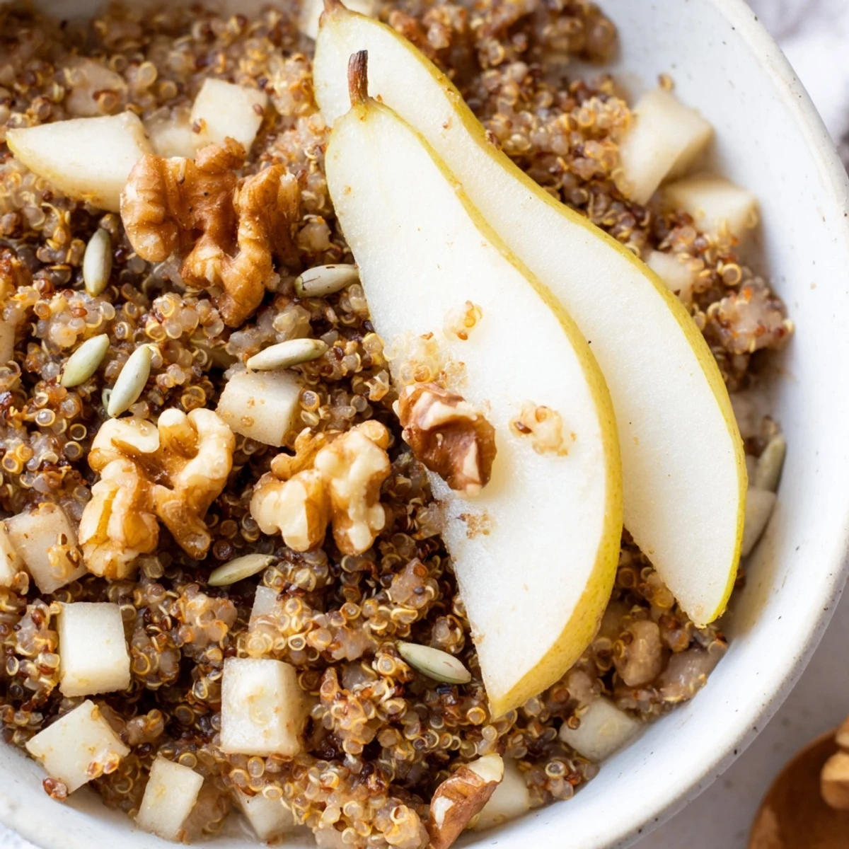 Healthy quinoa breakfast bowl with almond milk, ginger, nutmeg, and walnuts, perfect for a gluten-free, naturally sweet morning.