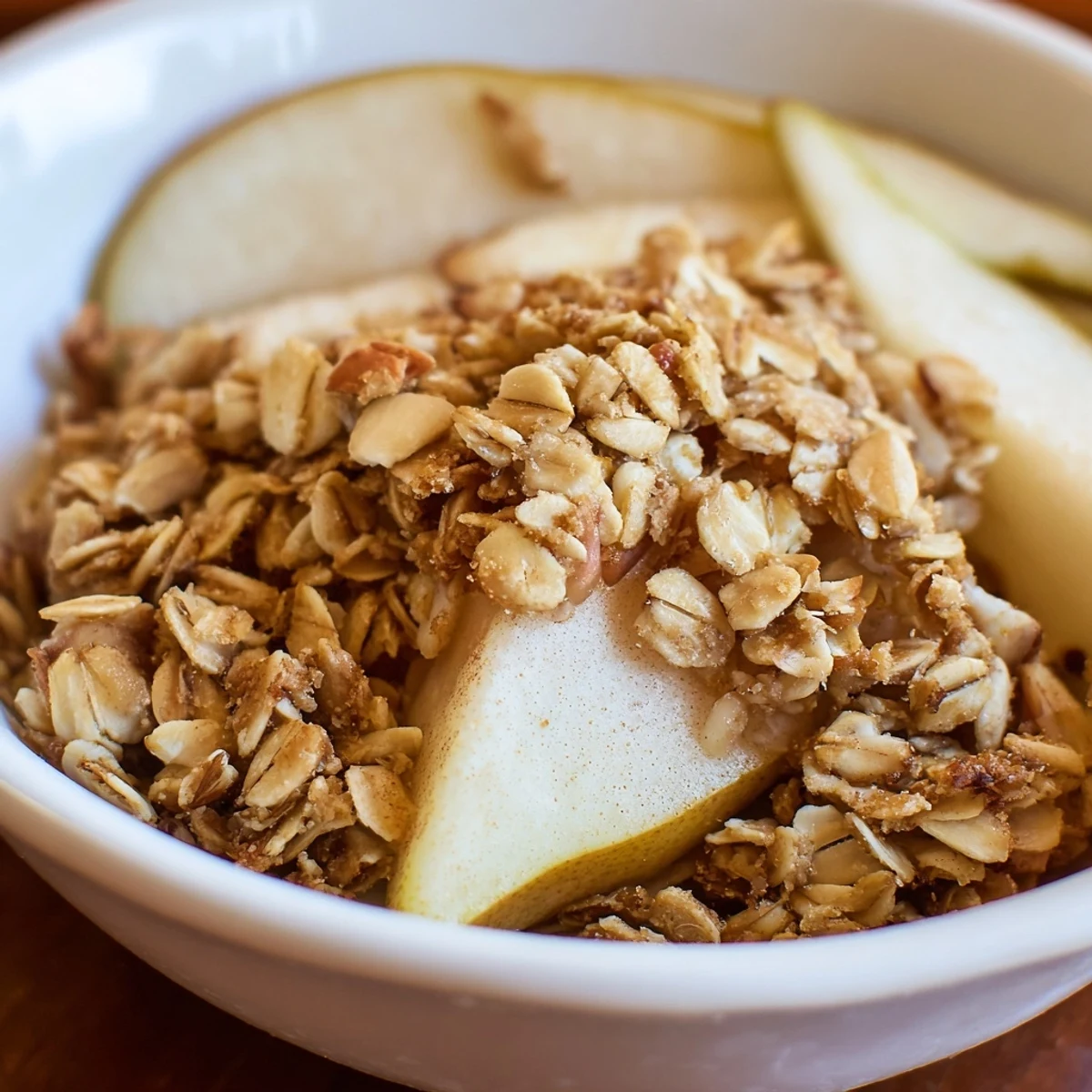 A close-up view of Oat Topped Maple Almond Crisp with a drizzle of maple syrup over the fruit filling.