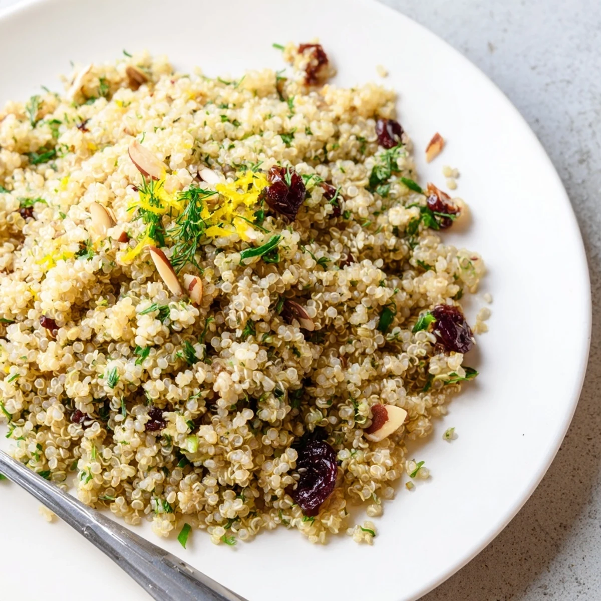 Fluffy quinoa and herb pilaf with citrus zest, served warm from a white bowl for a bright, light side dish.