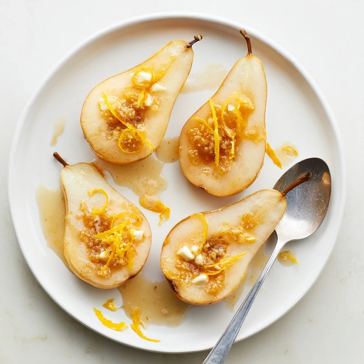 Warm ginger fresh citrus baked pears are served in shallow bowls with a spoonful of pan sauce and a dollop of vanilla ice cream.