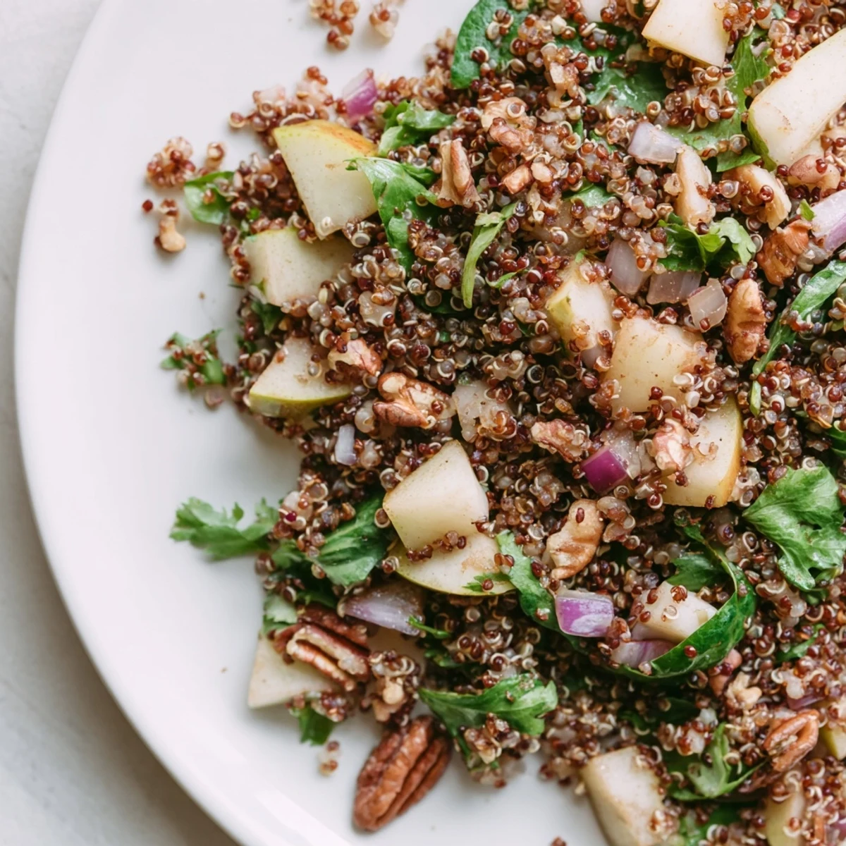 Pear and Spice Toasted Quinoa Salad in a white bowl, featuring toasted pecans and baby spinach.  
