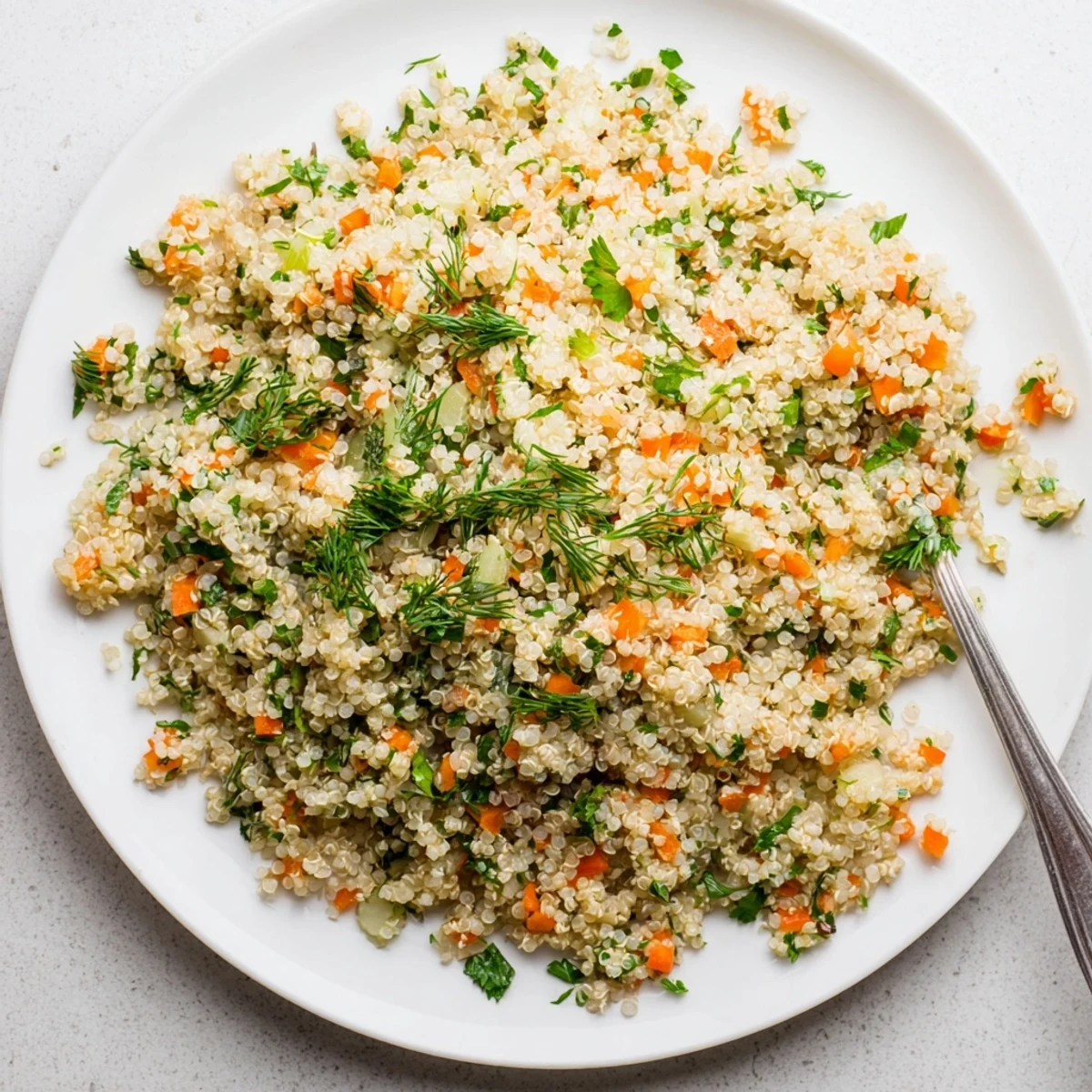 Steaming quinoa and herb pilaf with grated carrot and celery, garnished with fresh thyme, in a white ceramic bowl.  