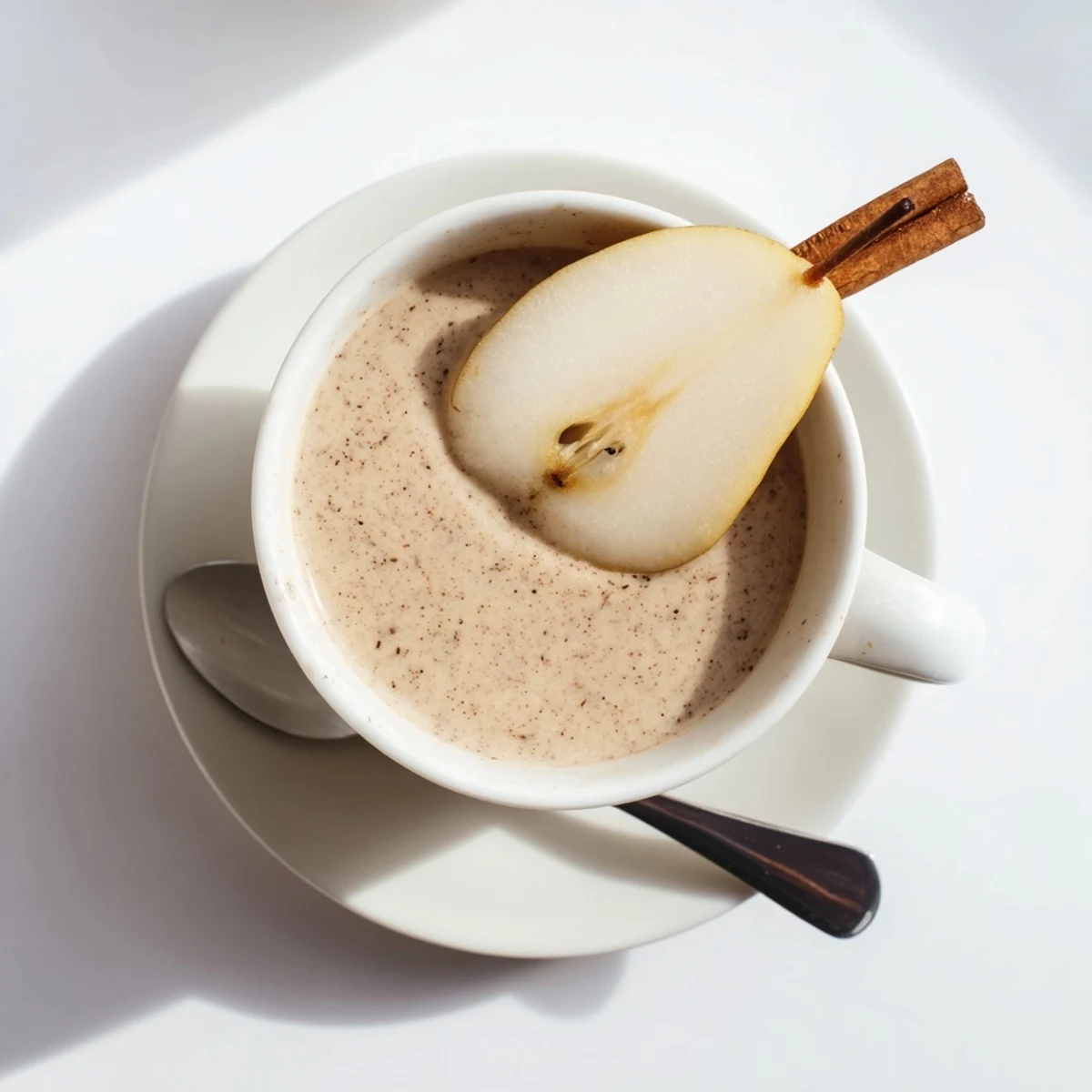 A steaming mug of Pear & Ginger Scented Cinnamon Warm Smoothie with a cinnamon stick garnish.