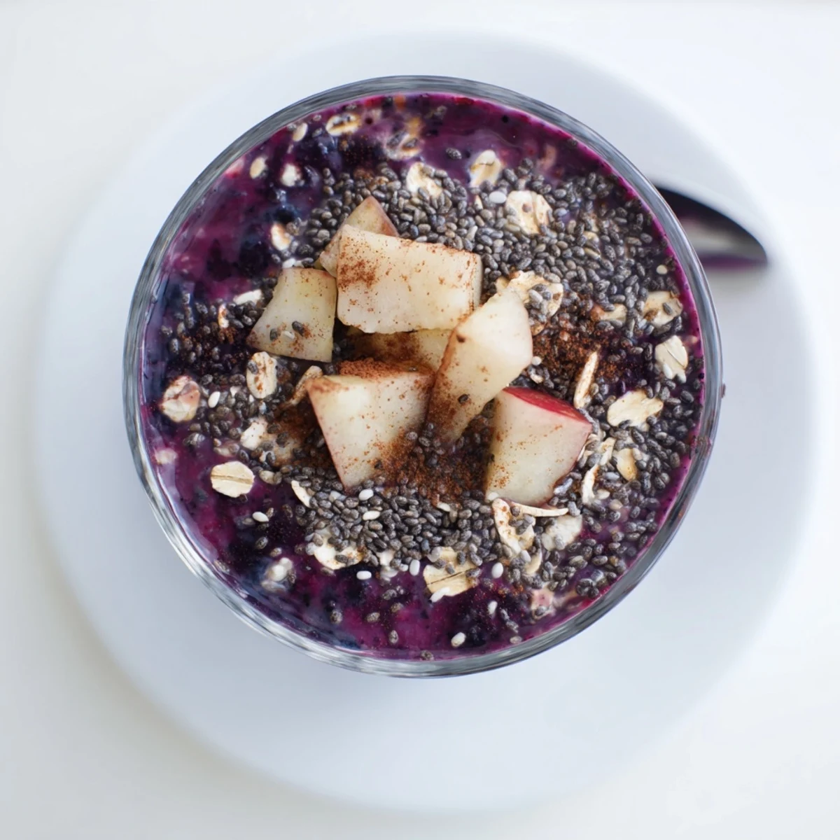 Thick, frothy pear and spice blueberry oat smoothie garnished with a cinnamon stick and rolled oats.