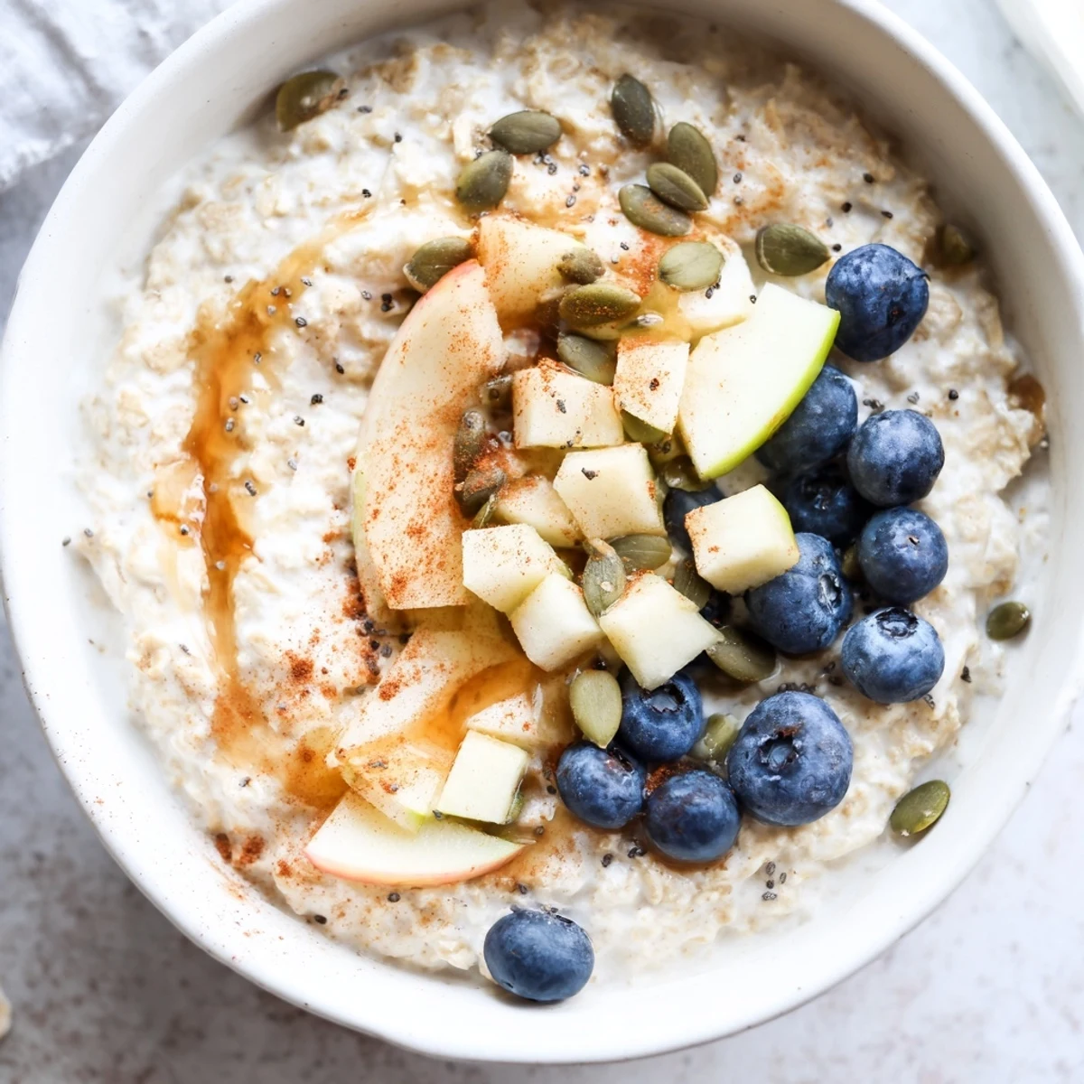 Creamy Banana-Free Porridge in a rustic bowl, topped with diced apple, fresh blueberries, and walnuts, steam rising for a warm breakfast.