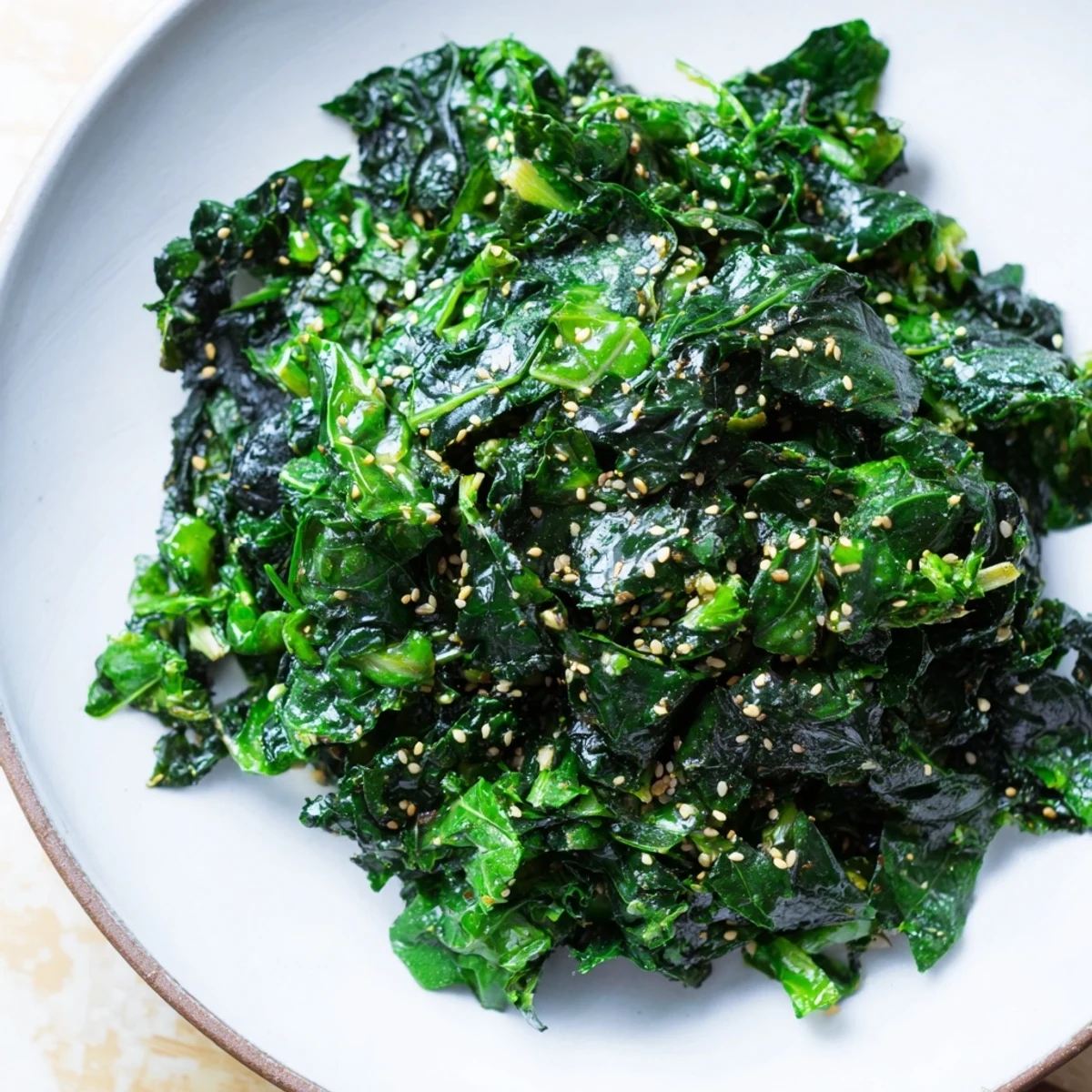 Braised Winter Greens with Warming Miso Glaze in a skillet, with vibrant green leaves tossed in a rich, sticky miso sauce and topped with toasted sesame seeds.