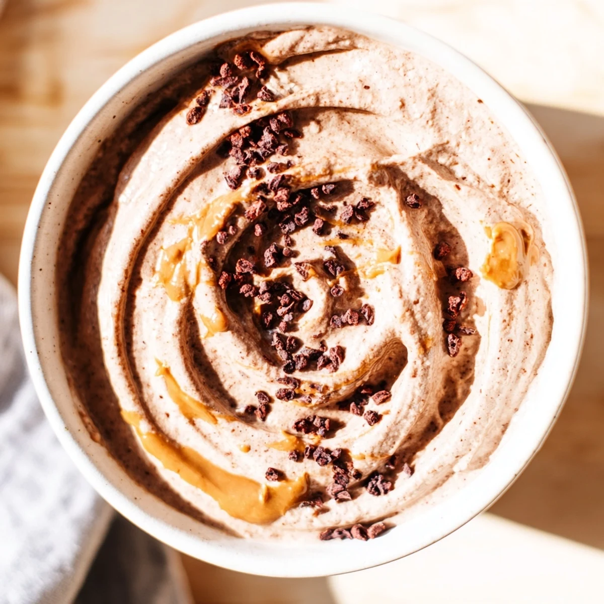 A bowl of creamy Immune Boosting Cocoa Banana Nice Cream topped with fresh raspberries and a drizzle of almond butter.  