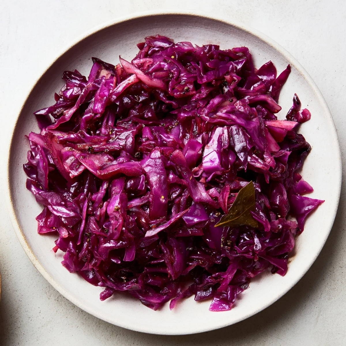 In a ceramic dish, steaming Braised Red Cabbage with tender apple slices and onions.