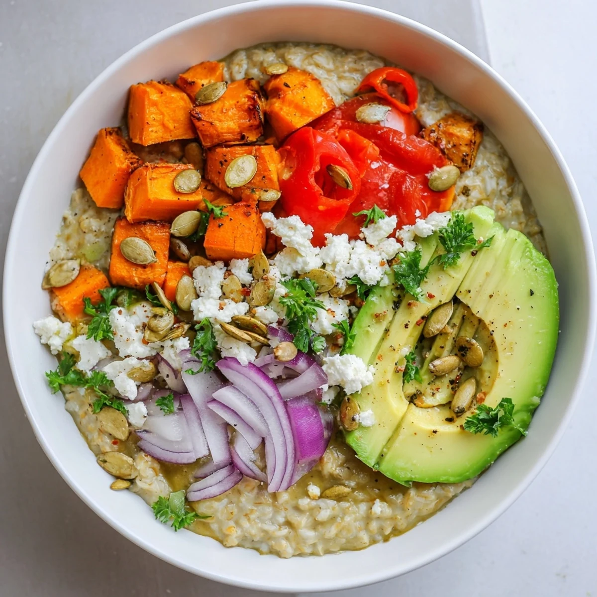 Steaming Savory Slow-Roasted Oat Bowl garnished with roasted red peppers, feta cheese crumbles, and fresh parsley.