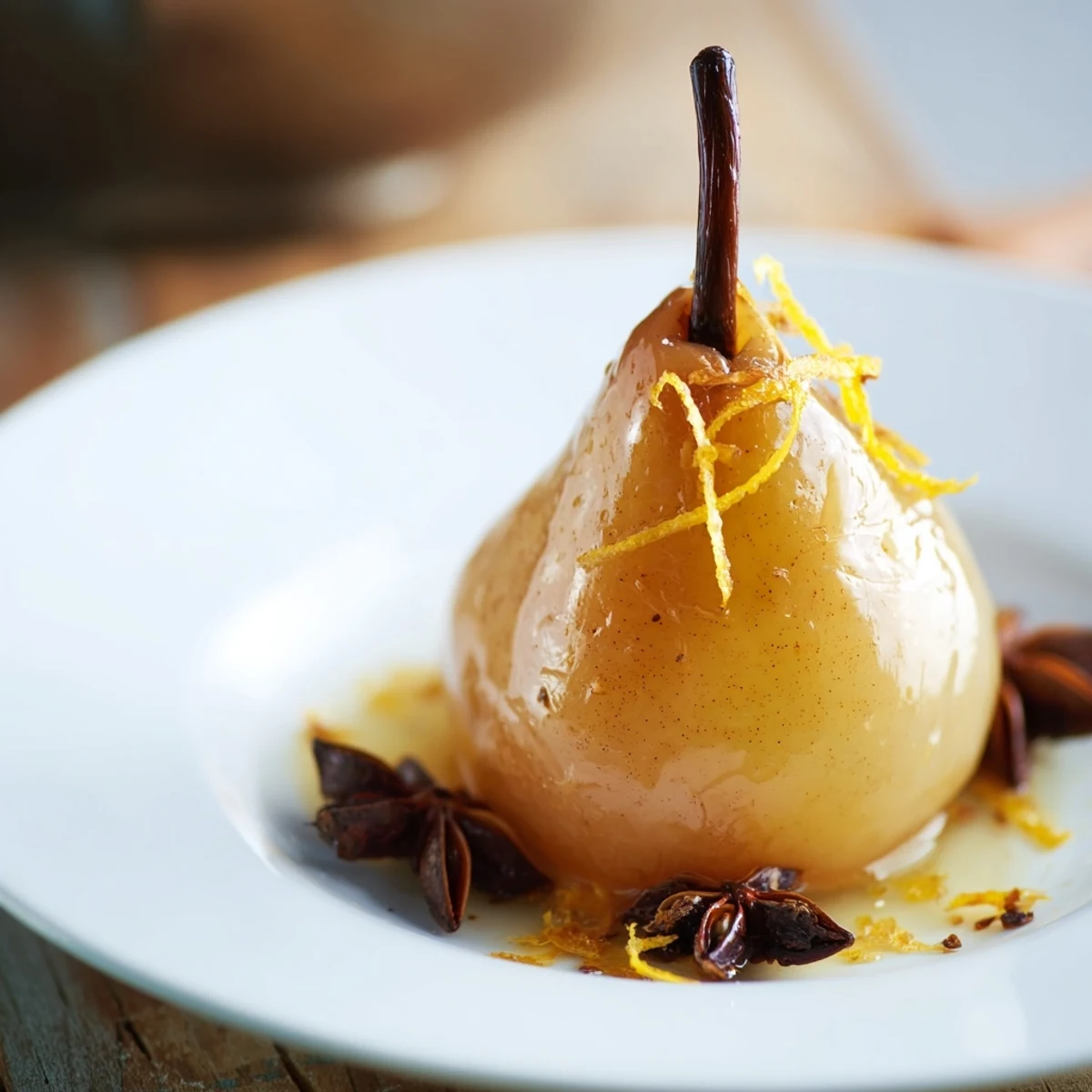 Warm-spiced pears glistening with fragrant orange syrup in a white dish. Poached Pear in Warm Spice Orange Kissed recipe served with a vanilla ice cream scoop.