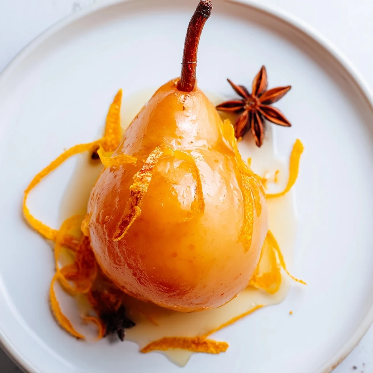 A close-up of tender Poached Pear in Warm Spice Orange Kissed, drizzled with syrup and garnished with star anise and cinnamon stick.