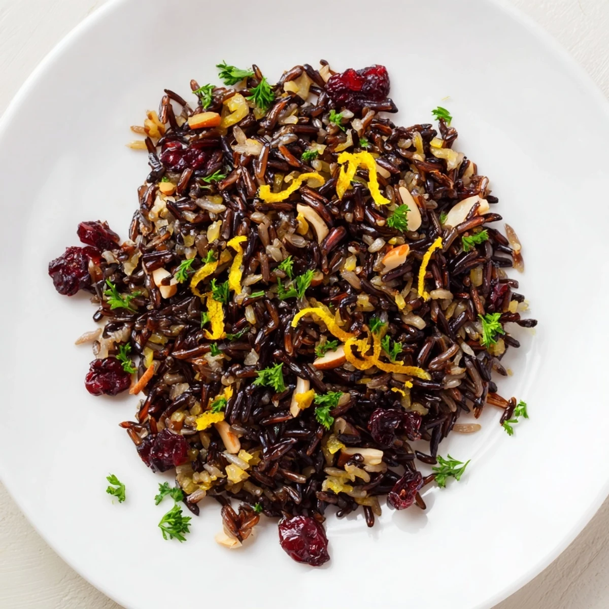 Steam rises from a warm bowl of Wild Rice Citrus Pilaf with Rosemary, garnished with parsley and served alongside a roasted chicken.