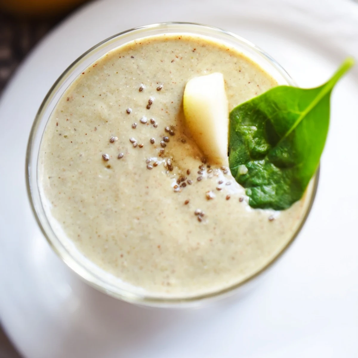 Enjoy a tall glass of Ginger Pear Spinach Smoothie with ice, spinach, and pear chunks.