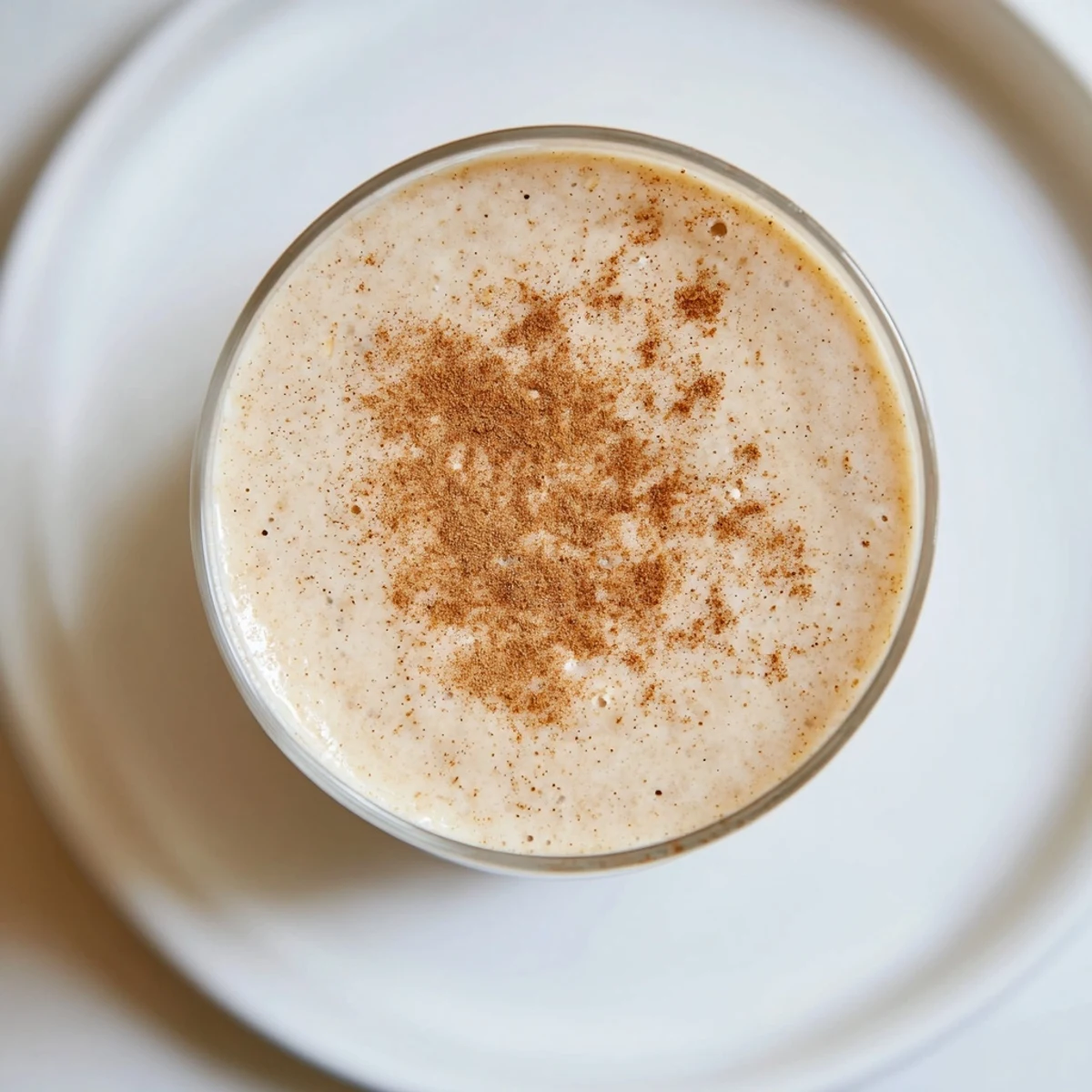 Creamy Spiced Apple Oat Smoothie with diced apples and cinnamon, served chilled in a tall glass.