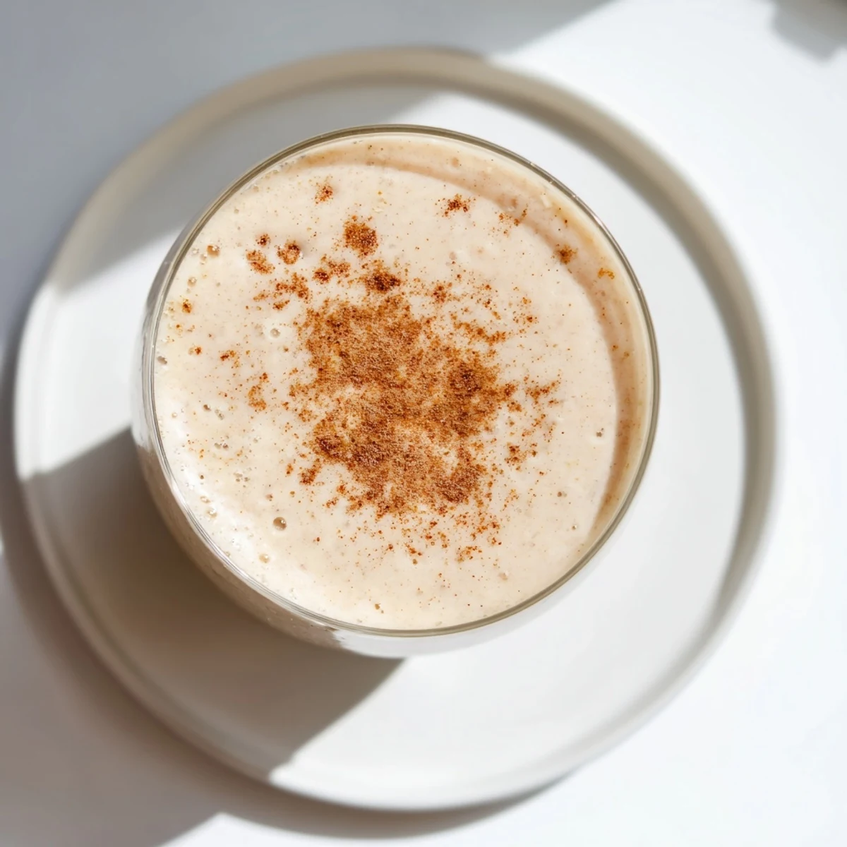 A refreshing Spiced Apple Oat Smoothie blended with almond milk and Greek yogurt, topped with nutmeg.