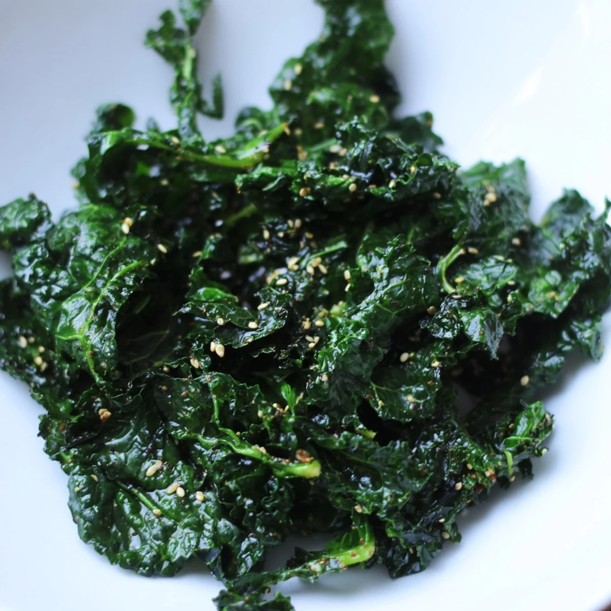 Freshly prepared Smoky Miso Kale Sauté garnished with sesame seeds in a rustic skillet on a wooden table.
