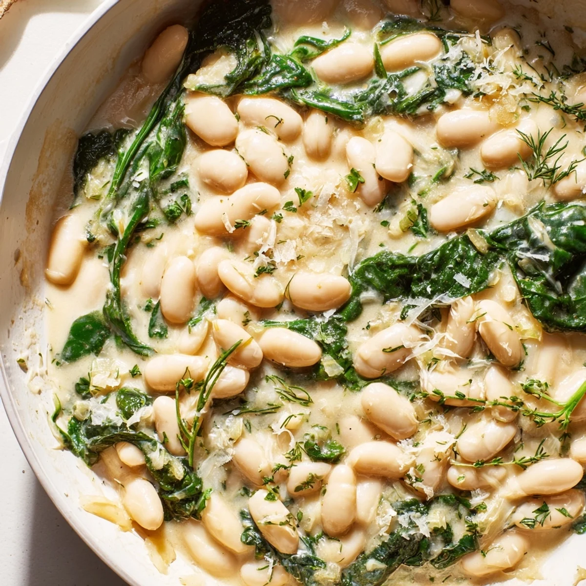 Golden-brown onions and garlic simmer in a creamy white bean sauce with wilted spinach in this one-pan skillet dinner.