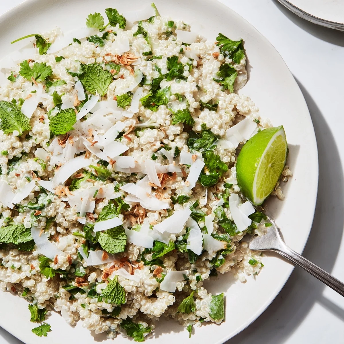 Heaping bowl of Coconut Lime Quinoa With Fresh Herbs, served with lime wedges beside grilled shrimp.