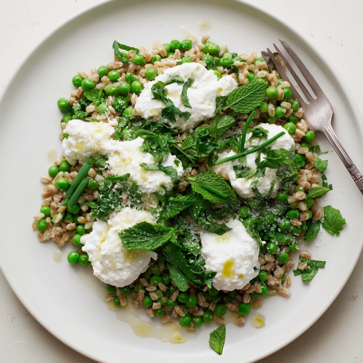 A close-up of Lemon Ricotta Farro With Spring Herbs showing creamy white ricotta dollops on chewy grains.