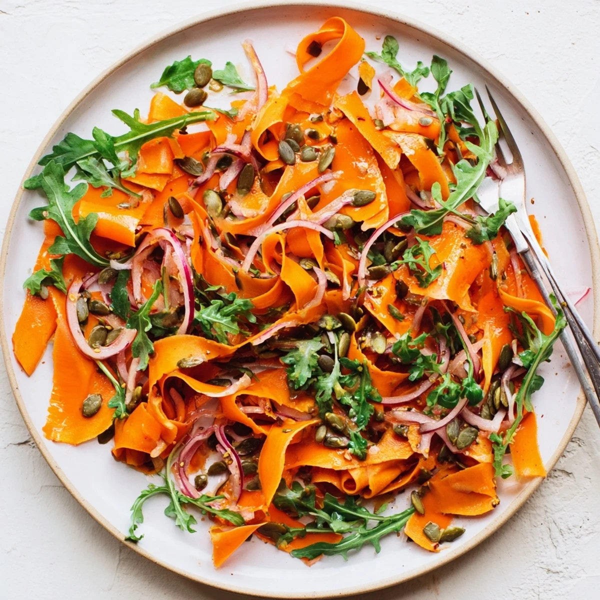 Roasted carrot ribbons glisten with citrus dressing in this vibrant salad garnished with pepitas and parsley.