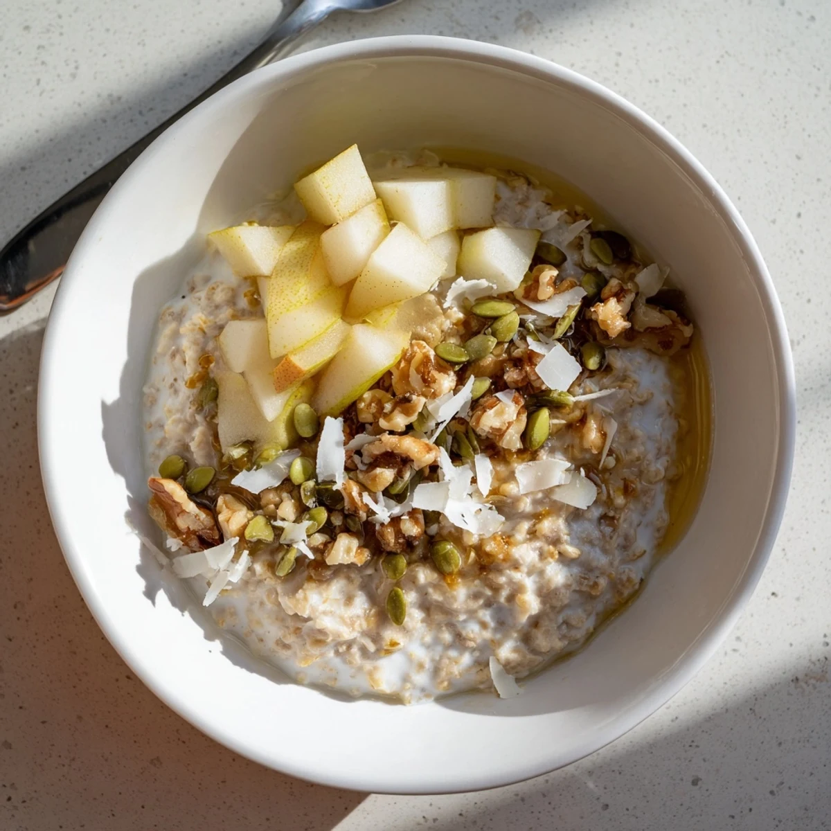 Creamy overnight oats topped with diced pears and crunchy walnuts, drizzled with honey.