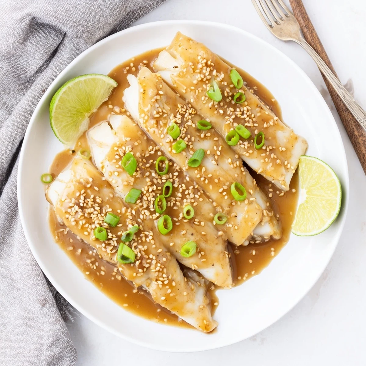 Four flaky Miso Maple Glazed Cod pieces are arranged on a baking sheet, covered in a glossy, savory-sweet glaze ready for dinner.