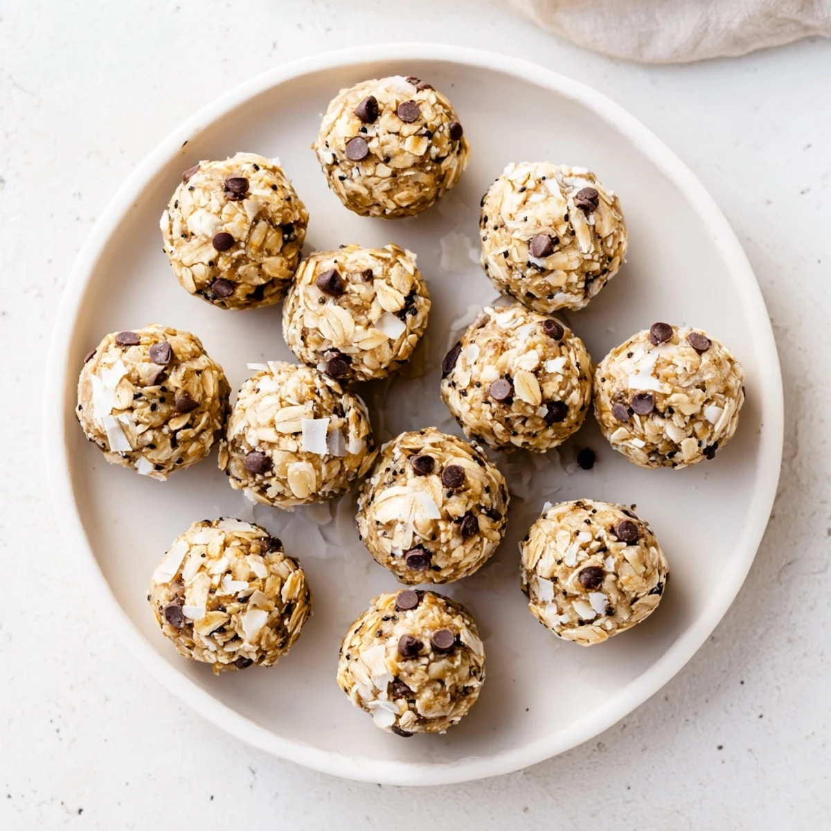 Freshly rolled Vanilla Almond Oat Energy Bites lined on parchment, showcasing chewy oats and crunchy almond bits.