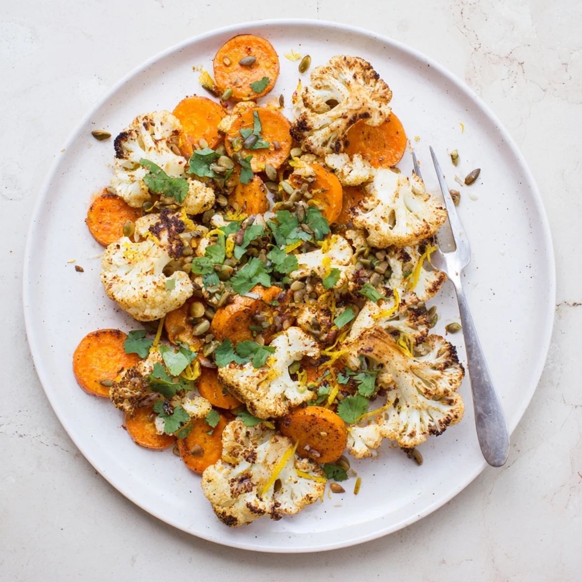 Warm Spiced Cauliflower and Carrot Medley served alongside grilled chicken, garnished with lemon zest for brightness.