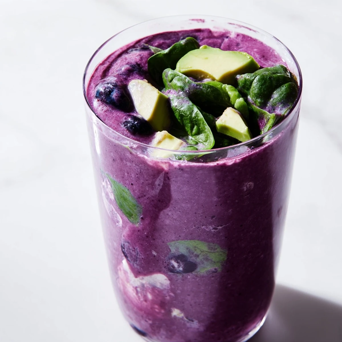 Creamy Blueberry Avocado Spinach Smoothie served in a tall glass garnished with fresh blueberries and a sprinkle of chia seeds.