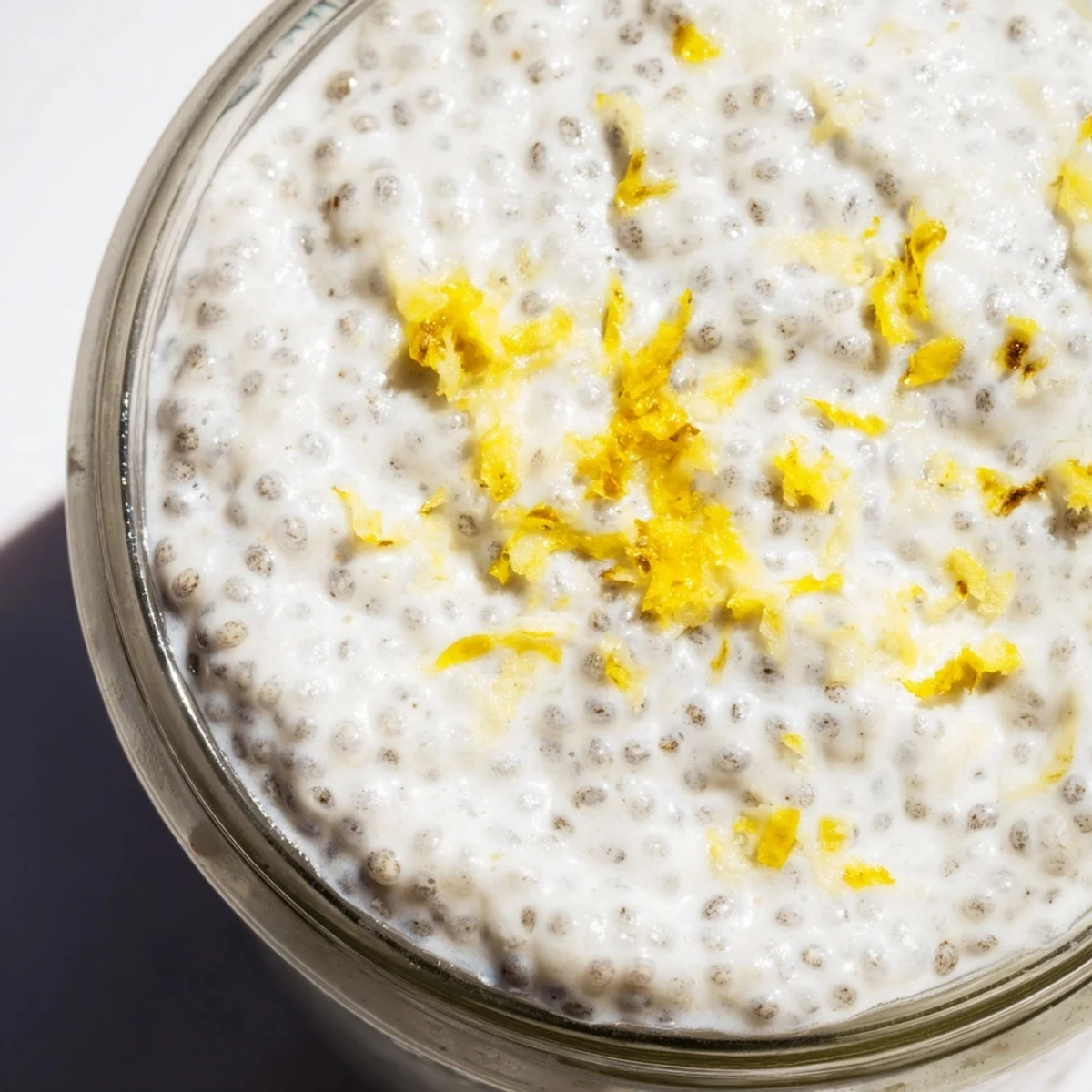 Creamy lemon poppy seed chia pudding topped with fresh berries and coconut flakes in a glass jar