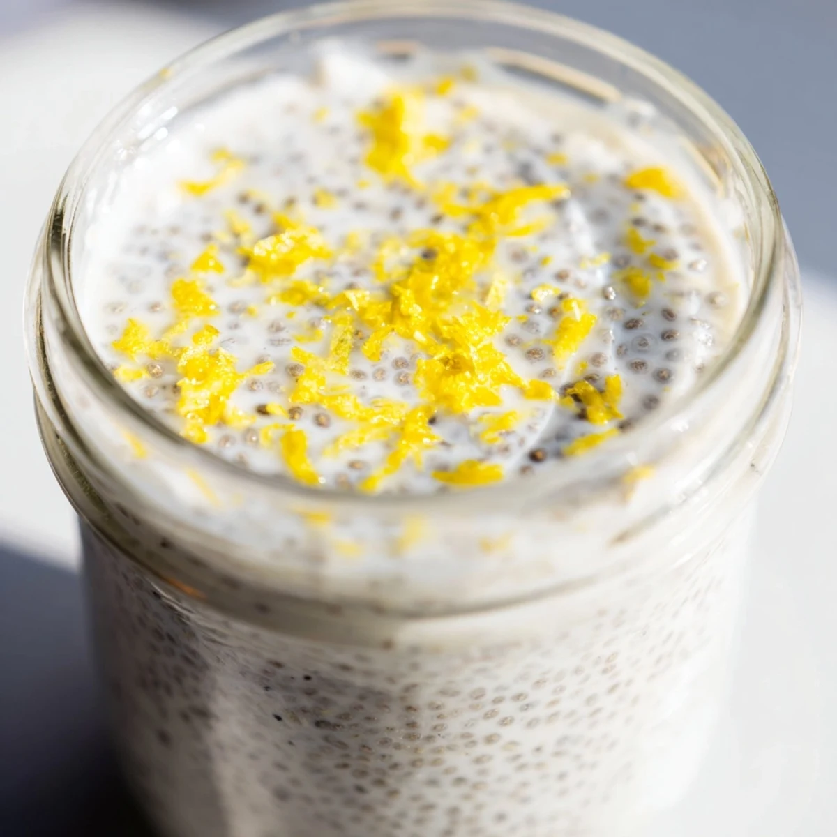 Zesty lemon poppy seed chia pudding with visible chia seeds and vibrant yellow lemon zest garnish