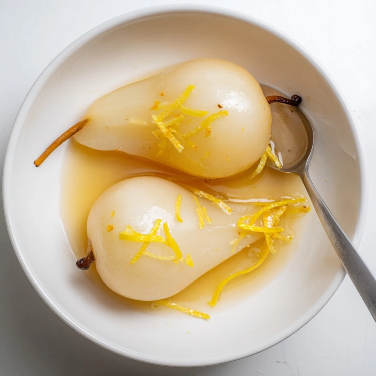 Golden vanilla citrus poached pears swimming in a fragrant orange lemon syrup