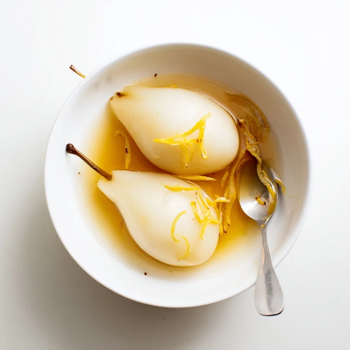 Tender French dessert pears elegantly plated with glistening citrus vanilla poaching liquid