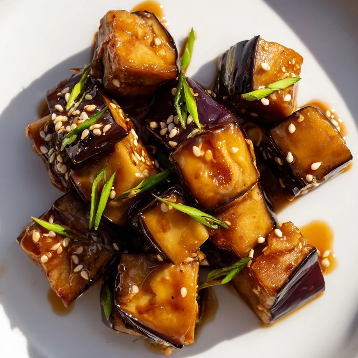 Golden brown roasted eggplant cubes glazed in rich ginger soy sauce with sesame seed garnish