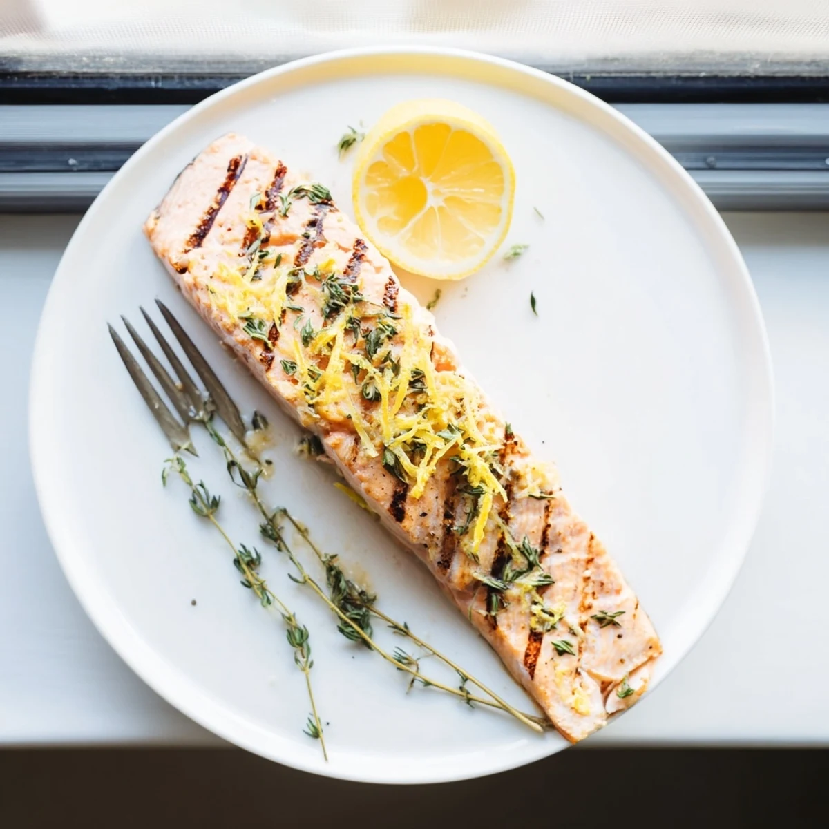 Golden lemon thyme grilled salmon fillets with charred grill marks and fresh herb garnish