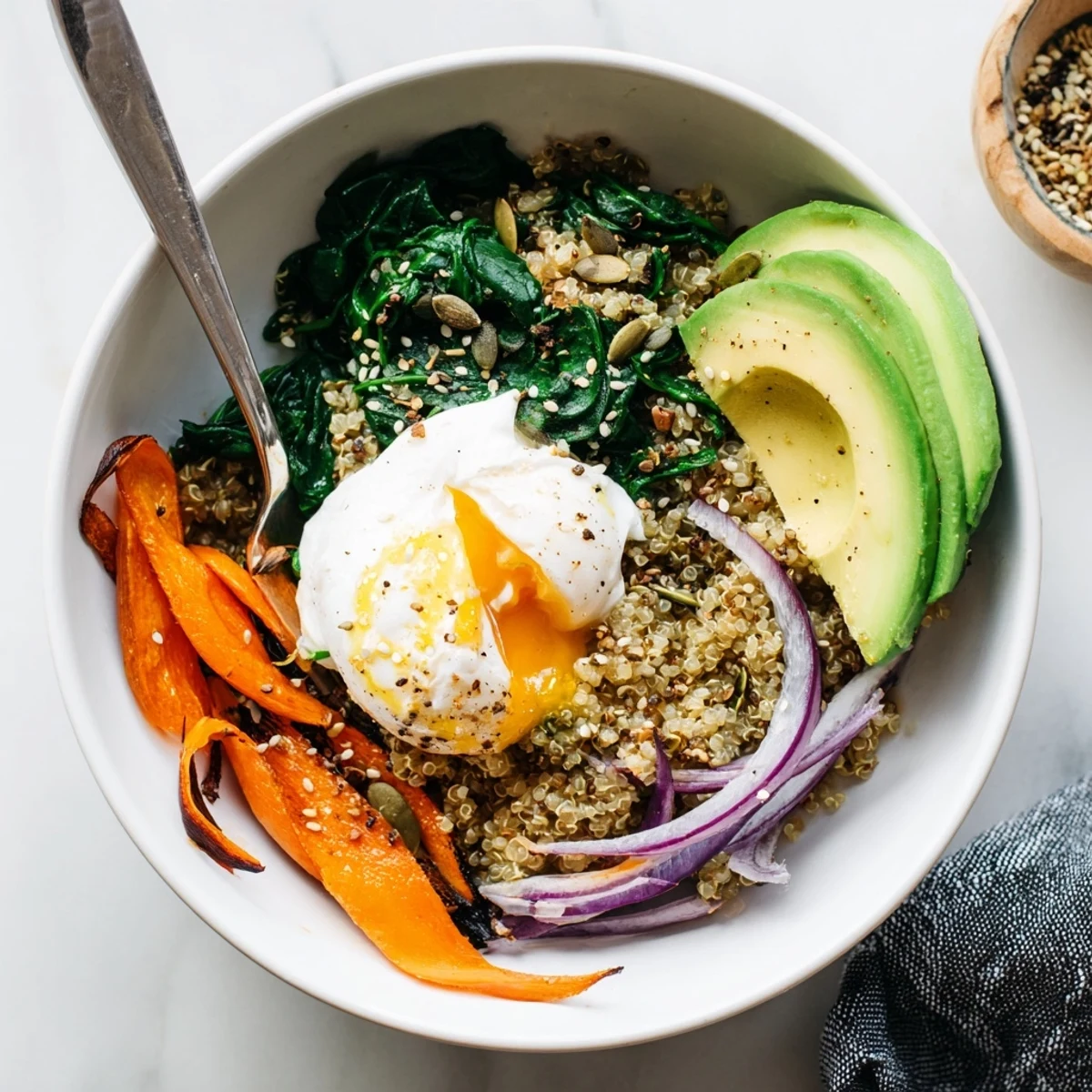 Nutritious morning meal with sautéed spinach and carrots, runny poached egg, fresh avocado, and a sprinkle of sunflower and pumpkin seeds