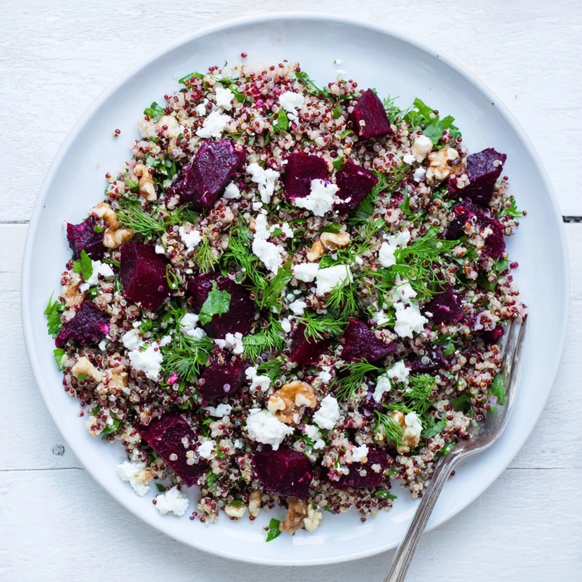 Colorful quinoa herb and roasted beet salad drizzled with zesty lemon vinaigrette in a white bowl