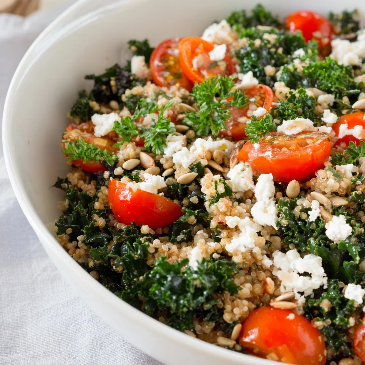 Warm savory kale and tomato amaranth breakfast bowl sprinkled with fresh herbs and pumpkin seeds