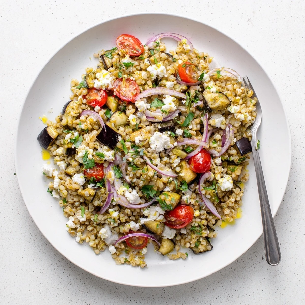 Golden roasted eggplant and fluffy bulgur salad tossed with fresh herbs and colorful vegetables in a Mediterranean-style bowl