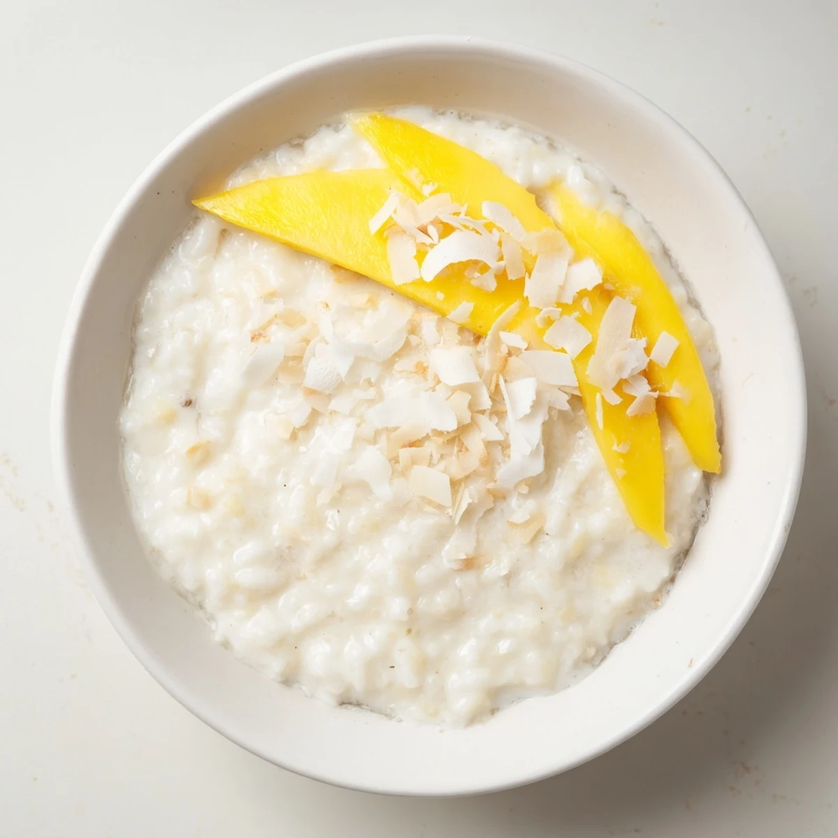 Creamy vanilla coconut rice pudding sprinkled with toasted coconut garnish in white bowl